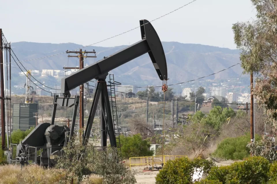 An oil well is pictured with buildings in the city of Los Angeles in the background.